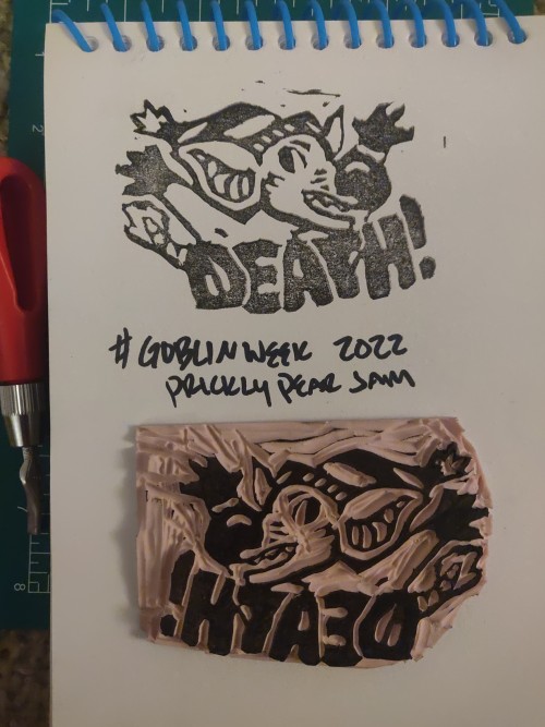 A black ink stamp and it's rubber negative. The stamp is of a possum-like goblin shouting 'DEATH!' with its arms raised.